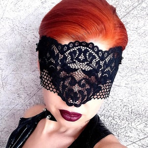 May include: A black lace eye mask with a delicate floral pattern. The mask covers the eyes and part of the forehead.