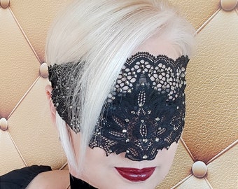 May include: A black lace eye mask with rhinestones. The mask is worn over the eyes and covers the bridge of the nose.