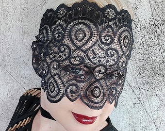 May include: A black lace mask with rhinestones, covering the eyes and part of the face. The mask has a delicate, intricate design.