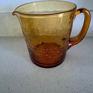 May include: Amber glass pitcher with a textured surface and a handle.