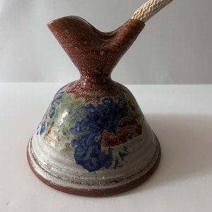 May include: A ceramic oil lamp with a brown, white, and blue glaze. The lamp has a spout and a wick.