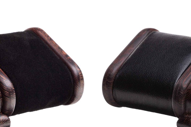 May include: Two black suede watch cushions with brown wood frames. The cushions are rectangular and have rounded edges. The wood frames have a dark brown finish and a wood grain pattern.