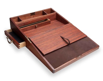 Op de afbeelding: Een bureau van mahoniehout met een lederen schrijf oppervlak, een uittrekbare lade en een scharnierend deksel. Het bureau heeft messing beslag en een leren riem.