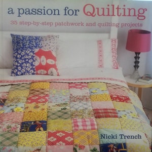 May include: A book cover titled "a passion for Quilting" with the text "35 step-by-step patchwork and quilting projects." The image shows a bed with a patchwork quilt and pillows. A pink lamp sits on a side table.