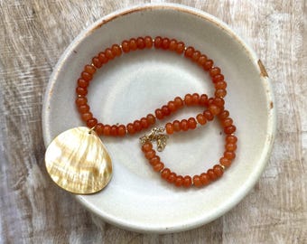 Orange golden hour beaded necklace with gold accents and shell pendant