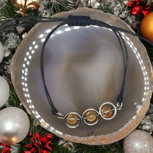 May include: A black cord bracelet with three round amber beads in silver settings.