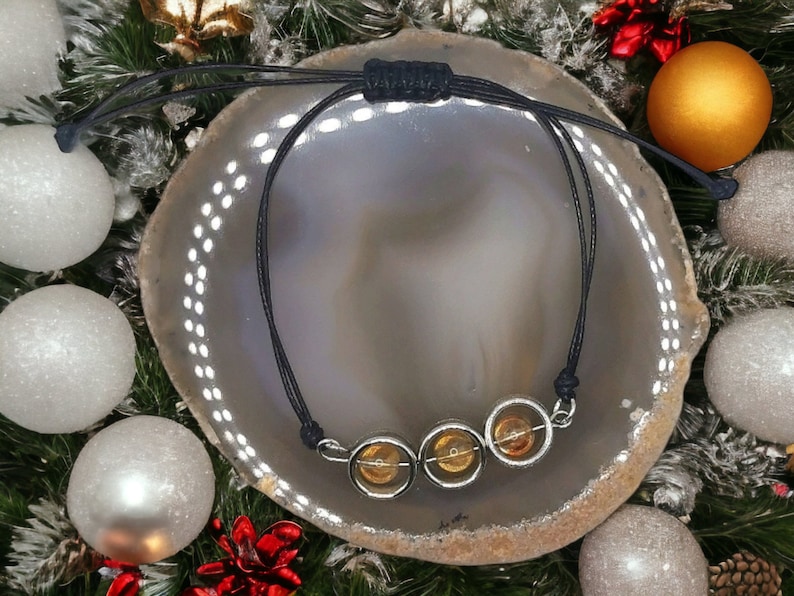 May include: A black cord bracelet with three round amber beads in silver settings.