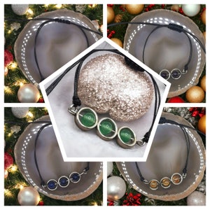May include: Three necklaces with different colored stones. Each necklace has three stones in a row, with a silver setting. The stones are green, blue, and orange.