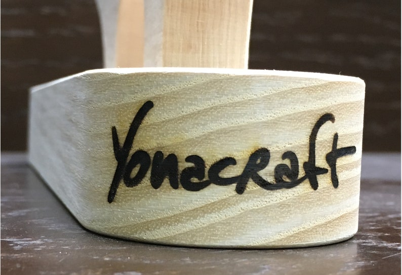 Puede incluir: Primer plano de un objeto de madera con la palabra "Yonacraft" grabada en la parte inferior.