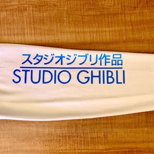 May include: White long-sleeve shirt with blue text that reads "スタジオジブリ作品 STUDIO GHIBLI".
