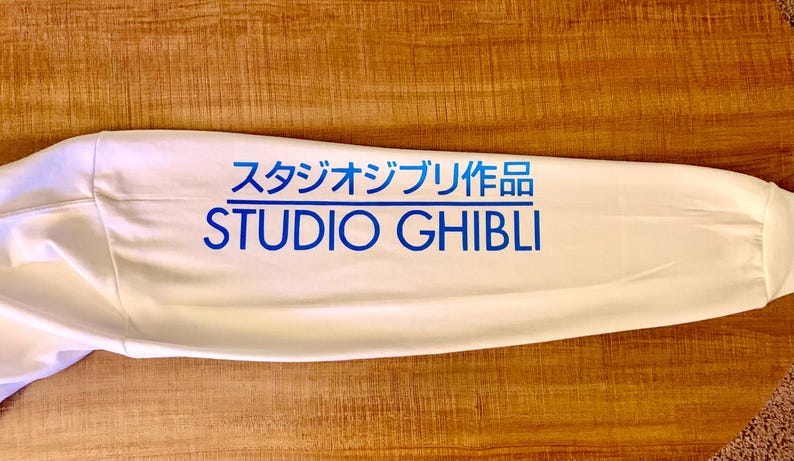 May include: White long-sleeve shirt with blue text that reads "スタジオジブリ作品 STUDIO GHIBLI".