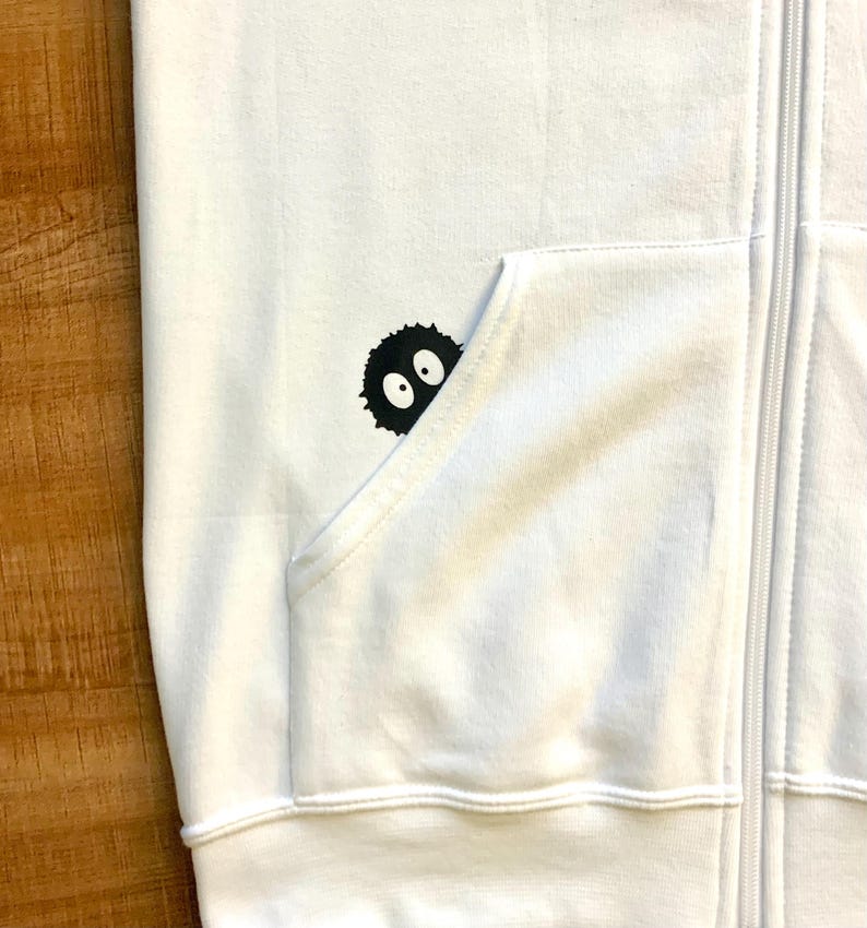 May include: White zippered hoodie with a black and white graphic of a cartoon character with two eyes peeking out of a pocket.