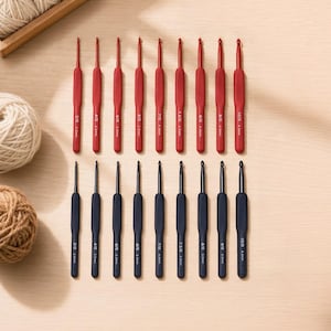 May include: A set of eighteen crochet hooks arranged in two rows, with nine red hooks on top and nine black hooks on the bottom. Each hook features printed size markings ranging from 2.0mm to 6.0mm, with a smooth handle and a metal hook tip.