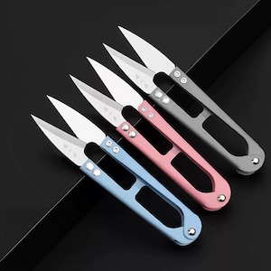 Peut inclure: Trois coupe-fils avec des lames en métal argenté tranchantes et des poignées bleu clair, rose et gris. Chaque outil présente un design ajouré dans la poignée, deux rivets argentés près du pivot et des caractères chinois gravés sur la lame.