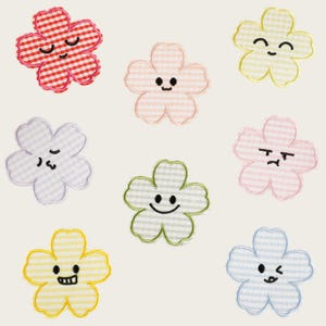 Könnte beinhalten: Acht gestickte Blumenaufnäher in verschiedenen Pastell- und leuchtenden Farben mit Vichy-Karo-Muster. Jede fünfblättrige Blume zeigt einen einzigartigen gestickten Gesichtsausdruck, darunter lächelnde, zwinkernde und mürrische Gesichter in schwarzem Garn.