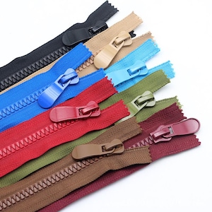 May include: A collection of eight plastic zips in various colours including black, beige, bright blue, light blue, red, olive green, brown, and maroon. Each zip features a matching plastic pull tab attached to a slider on the teeth.