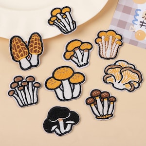 May include: A collection of nine embroidered mushroom patches featuring various species in shades of yellow, brown, black, and white. Each patch displays detailed stitching of caps and stems, showcasing diverse fungal shapes including morels and clusters.