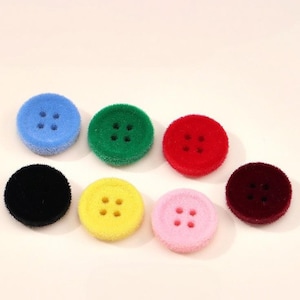 May include: A collection of seven round, four-hole buttons with a fuzzy, textured surface. The buttons are available in a variety of vibrant colors including blue, green, red, black, yellow, light pink, and deep burgundy.