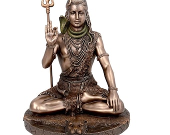 May include: A bronze statue of Shiva, a Hindu deity, sitting in a meditative pose. He is holding a trident in his right hand and has a snake around his neck. He is sitting on a tiger skin and a tiger head is visible at the base of the statue.