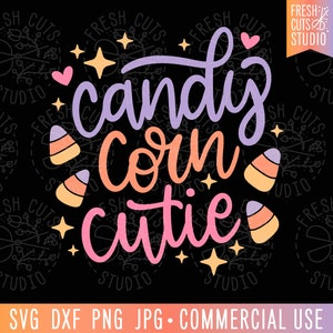 May include: A purple, orange, and pink graphic design with the text "candy corn cutie" and images of candy corn. The design is surrounded by a black background with a white pattern of stars and leaves.