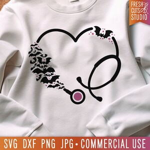 May include: White sweatshirt with a black stethoscope design in the shape of a heart. Bats and stars are scattered around the stethoscope. The text "FRESH CUTS STUDIO" is in the top right corner of the image.