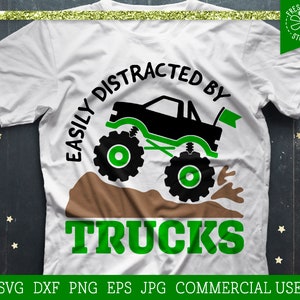 May include: A white t-shirt with a green and black graphic of a monster truck with the text "Easily Distracted By Trucks".