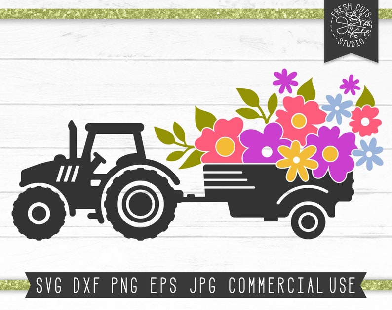 May include: A black tractor pulling a wagon filled with colourful flowers. The flowers are pink, purple, yellow, and blue. The tractor has a large front tyre and a smaller back tyre.