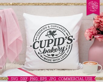 Op de afbeelding: Wit kussen met een zwart-wit logo met de tekst "Cupid's Bakery" met een hartje en de tekst "Cookies & Cupcakes" en "Made with Love".