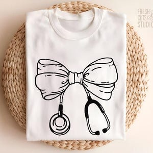 May include: White t-shirt with a black and white illustration of a bow tie and stethoscope. The text "Fresh Cuts Studio" is in the top right corner of the image.