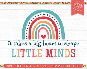May include: A colorful rainbow with a red heart in the center and the text "It takes a big heart to shape LITTLE MINDS" below. The image is on a white wood background.