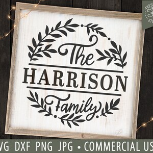 May include: A white wooden sign with black text and a wreath of leaves. The text reads "The Harrison Family".