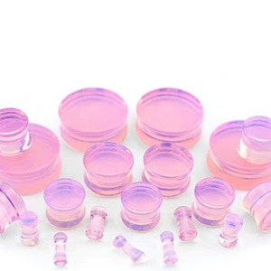 May include: A set of iridescent pink acrylic ear gauges in various sizes. The gauges are made of clear acrylic with a pink iridescent finish. The set includes a variety of sizes, from small to large.