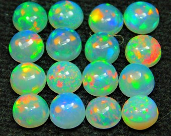 May include: A collection of 16 round, iridescent opal cabochons. The opals are a mix of white, green, blue, and orange.
