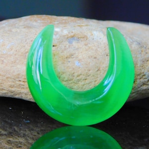 Peut inclure: Un jauge d'oreille en forme de fer à cheval en verre vert brillant. La jauge est lisse et brillante.