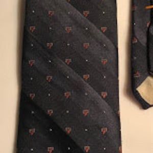 May include: A dark gray tie with a diagonal striped pattern. The stripes are accented with small red heart-shaped designs. The tie is made of a smooth fabric and has a classic design. The tie is a standard length.