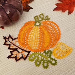 May include: A crocheted pumpkin with leaves in orange, green, and black. The pumpkin is surrounded by a brown wooden surface.