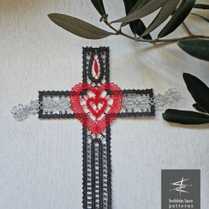 Può includere: Una croce in pizzo a fuselli nera e argentata con un cuore rosso al centro. La croce è realizzata con un delicato lavoro a pizzo e ha un design semplice ed elegante. Il cuore è un simbolo di amore e fede.