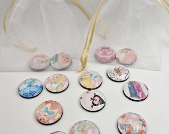 May include: A collection of round, glass-covered magnets featuring characters from Alice in Wonderland. The magnets are in a variety of colors and designs, and are displayed in small, sheer white bags with gold ribbon ties.