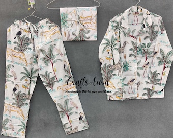 May include: White pajamas with a jungle print featuring zebras, birds, and palm trees. The pajamas include a long-sleeved shirt and pants.