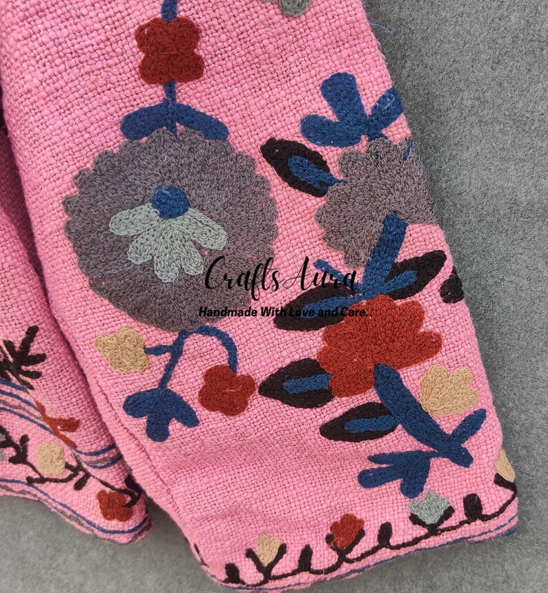 May include: Pink fabric with embroidered floral designs in shades of blue, brown, gray, and beige. The fabric has a textured woven appearance. The text "Crafts Aura Handmade With Love and Care" is visible in the center of the image.