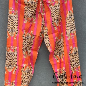 May include: Orange and pink striped pajama pants with a tiger print. The pants have a drawstring waist and are made of a soft, comfortable fabric.