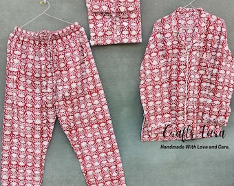 May include: A red and white patterned pajama set with a long-sleeved shirt and pants. The shirt has a button-up front and a collar. The pants have an elastic waistband. The fabric is soft and comfortable. "Crafts Aura Handmade With Love and Care."