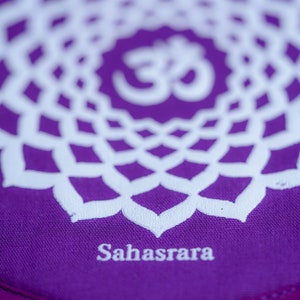 Op de afbeelding: Paarse meditatiekussen met een wit mandala-ontwerp en het woord "Sahasrara" gedrukt op de onderkant.