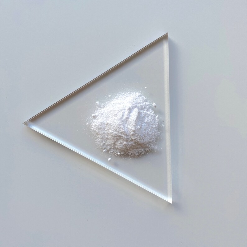 May include: A white powder on a clear triangular glass plate.
