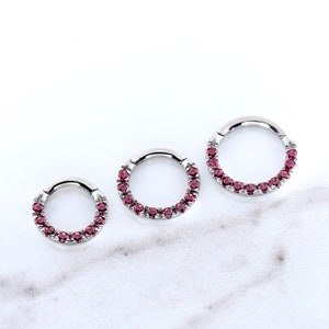 May include: Three silver seamless rings with a row of pink gemstones. The rings are different sizes.