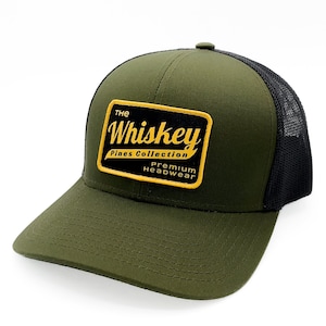 May include: A green and black trucker hat with a yellow and black patch that says "The Whiskey Pines Collection Premium Headwear".
