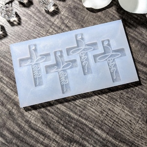 May include: A white silicone mold with four cross shapes. Each cross has the word "Love" written inside.