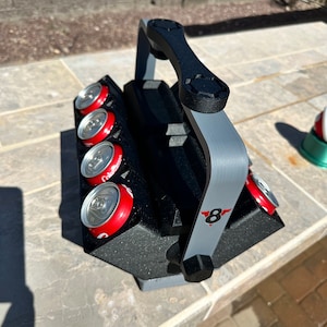 May include: A black and gray cooler with a handle and a red and white logo that says "8". The cooler is filled with six red and white cans.