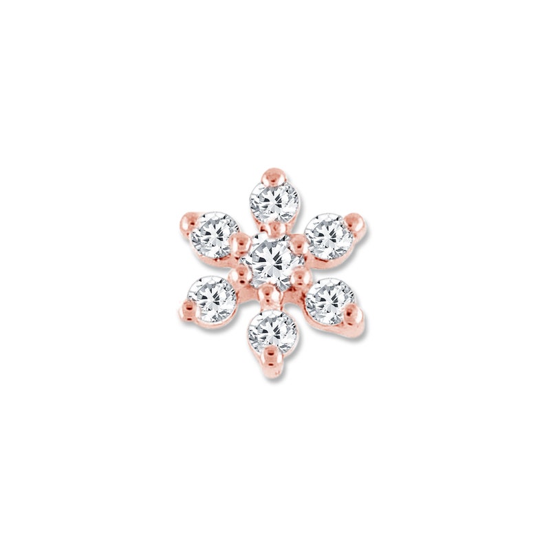 May include: A small, rose gold flower-shaped earring with clear cubic zirconia stones.