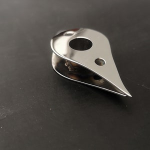 May include: A silver metal boat cleat with a teardrop shape and three holes.